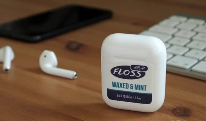 apple AirPods beside a floss container